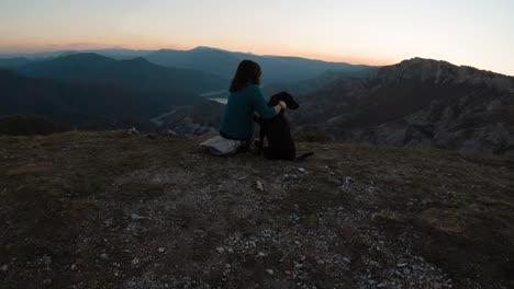 Mädchen-Sitzt-Und-Kuschelt-Schwarzen-Labrador-Hund-Auf-Einem-Berg