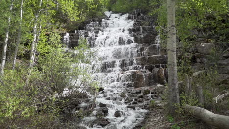 Zeitlupenaufnahme-Eines-Kaskadierenden-Wasserfalls-Im-Glacier-National-Park,-Montana,-Umgeben-Von-Espenbäumen-Mit-Gelben-Blättern