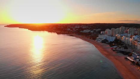 Great-Aerial-Shot-Zoom-out-from-the-sun,-in-Armação-de-Pêra-sunset-city-skyline