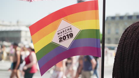 Die-Regenbogenfahne-Weht-Im-Wind-Vor-Der-Menge-Des-Gay-Pride-Marsches-In-Paris,-Frankreich