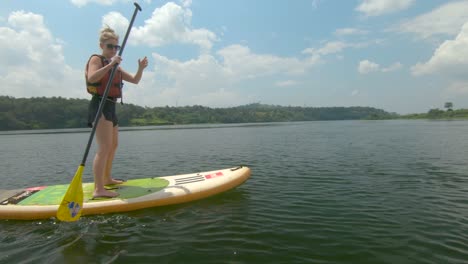 A-blonde-woman-paddles-into-some-reeds-on-a-stand-up-paddle-board-on-the-river-Nile-in-Africa