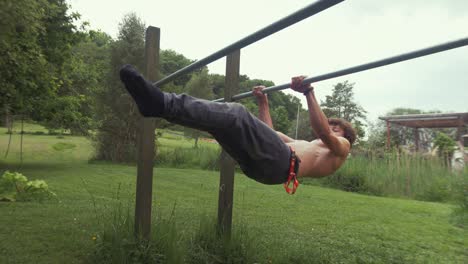 Young-fit-male-performs-front-lever-exercise-at-outdoor-home-gym-topless