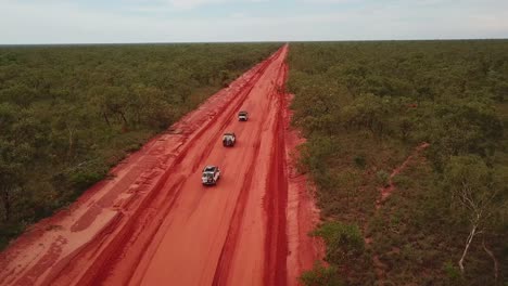 Aerial:-Drone-shot-tracking-three-4x4-vehicles-driving-in-convoy-on-the-red-dirt-Cape-Leveque-road-near-Broome,-Western-Australia
