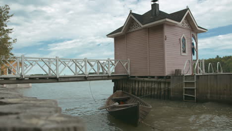 Wooden-Rowing-Boat-next-to-Small-Beach-Hut-with-a-Dock