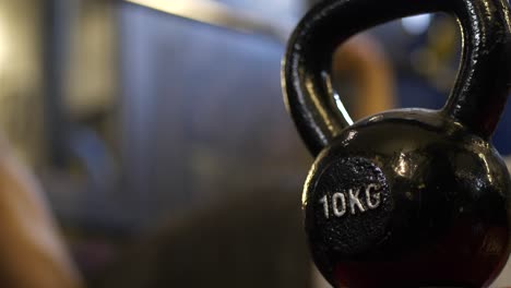 Close-shot-of-kettle-bell-in-gym,-Athlete-bench-pressing-in-blurry-background