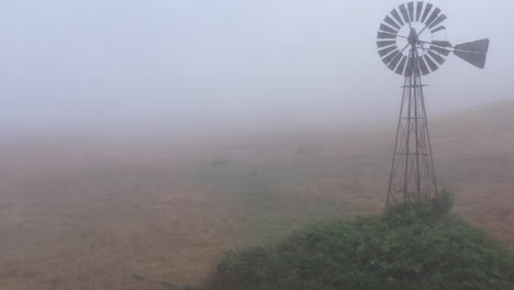 Aerial-flyby-with-tilt-reveal-of-antique-windmill-in-dense-fog
