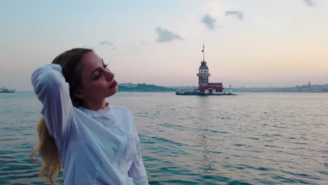 Slow-Motion:Beautiful-girl-enjoys-sunset-view-of-bosphorus-with-view-of-Maiden-Tower-at-background-in-Istanbul
