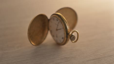 Push-in-to-focus-on-an-antique-pocket-watch-propped-open-on-a-light-grey-desk