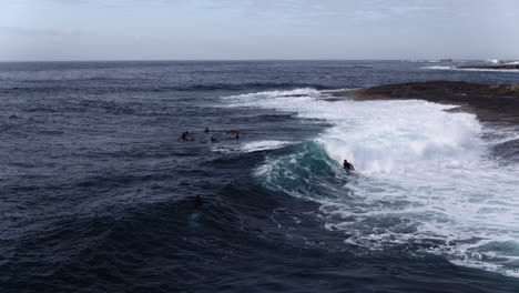 Aerial-tracking-a-group-of-Surfers-and-Bodyboarders-riding-waves-close-to-Rocks