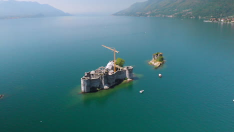 Fly-over-a-ruin-on-a-tiny-island-in-the-middle-of-Lake-Maggiore,-Italy