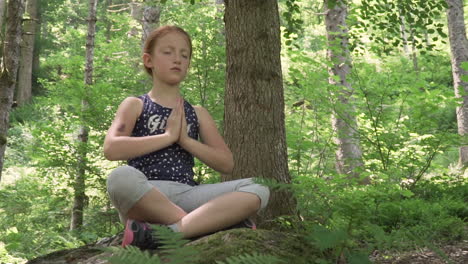 Little-girl-with-red-hair-meditates-in-the-woods-medium-shot,-slow-motion