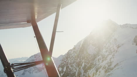 Aerial-fly-past-rocky-snow-covered-mountain-and-sunset