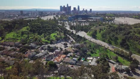 Aerial-of-baseball-stadium-perched-on-forested-hill-with-downtown-Los-Angeles-skyline-in-the-background