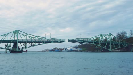 Oskara-Kalpaka-swing-bridge-closing-in-Liepaja-in-cloudy-autumn-day,-wide-shot