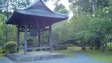 Große-Japanische-Glocke,-Umgeben-Von-Bäumen-In-Einem-Wunderschönen-Garten-Im-Hintergrund-In-Kyoto,-Japan,-Mittlere-Aufnahme,-Sanfte-Beleuchtung-4k