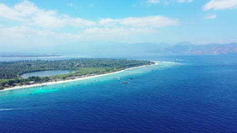 Friedliche-Meereslandschaft-Der-Blauen-Azurblauen-Lagune-Rund-Um-Die-Küste-Einer-Tropischen-Insel-Mit-Booten,-Die-In-Der-Nähe-Des-Weißen-Strandes-Am-Hellen-Himmel-Mit-Weißen-Wolken-In-Bali-Vor-Anker-Liegen