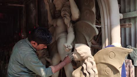 Poor-Indian-craftsman-working-on-making-clay-idols-of-Gods-and-Goddess-at-daytime-at-workshop