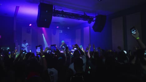 Atlanta,-GA---July-5,-2019:-A-crowd-of-millennials-and-young-people-cheer,-record-video-with-their-smartphones,-and-post-on-social-media-at-a-local,-underground-hip-hop-show