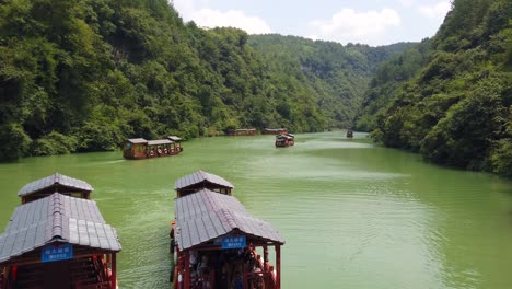 Zhangjiajie,-China---August-2019-:-Traditional-wooden-boats-sailing-on-the-waters-of-a-small-narrow-lake-between-tall-and-high-rocky-cliffs-of-the-majestic-Grand-Canyon-in-Zhangjiajie-National-Park