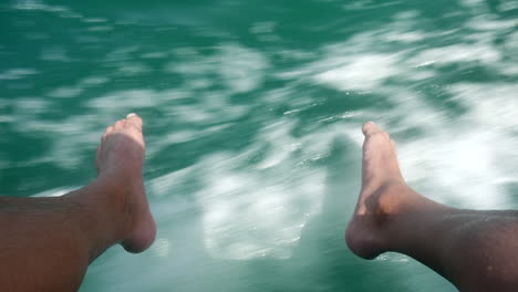 Männerfüße-Hängen-Vom-Boot-Hinunter-Ins-Wasser-Vom-Meer-In-Kroatien,-Istrien