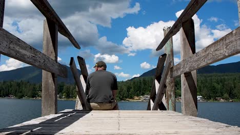 Man-on-wooden-dock-on-a-lake-looking-at-view-of-lake-and-sky