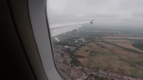 Vista-Desde-La-Ventana-De-Un-Avión-Sobre-El-Reino-Unido-En-Cámara-Lenta-Durante-Un-Día-Nublado