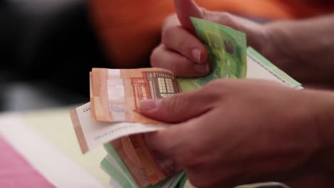 Male-hands-counting-euro-bills-of-100-and-50