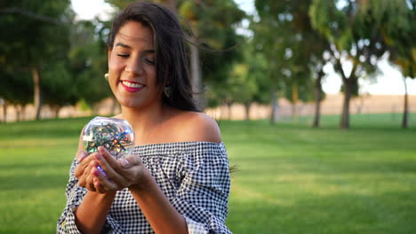 Eine-Süße-Hispanische-Frau-Lächelt-Glücklich-Und-Geht-Mit-Einer-Magischen-Kristallkugel-Durch-Einen-Park