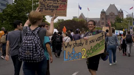 Queenspark,-Toronto,-Canada---A-student-happily-showing-her-placard-as-she-goes-with-the-crowd-in-the-street---slow-motion