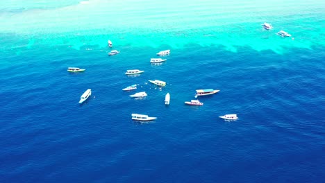 Maldives-Blue-Deep-Ocean-Showing-Boats-At-The-Middle-Of-It-Floating-Above-The-Water-Surface---Aerial-Shot