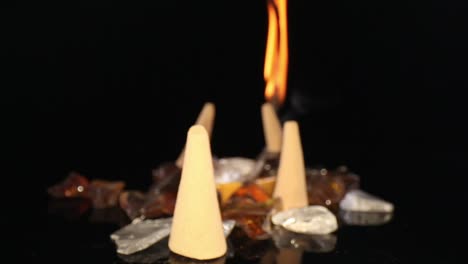 Pushing-past-several-unlit-incense-cones-in-a-decorative-rock-garden,-towards-a-lit-incense-stick-on-fire-with-smoke-billowing