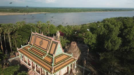 Hermosa-Pagoda-Con-Pájaros-En-Cámara-Lenta-Volando,-Al-Lado-Del-Pintoresco-Río-Mekong