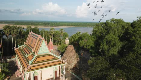 Beautiful-pagoda-with-slow-motion-birds-flying-over,-beside-the-scenic-Mekong-River