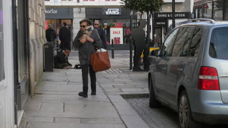 A-homeless-man-sitting-on-a-pavement-in-Truro-city-centre-being-ignored-by-passersby,-slow-motion