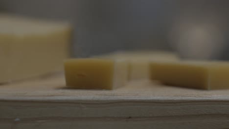 Gouda-cheese-pieces-rotating-on-wooden-table,-closeup---Portugal