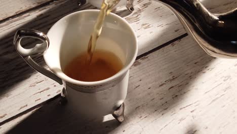 Slow-motion-extreme-closeup-of-tea-pouring-into-a-Turkish-cup-on-a-distressed-wood-table