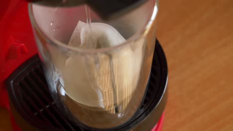 Pouring-water-into-a-transparent-glass-with-tea-bags-in-it