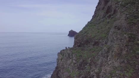 nobody-huge-mountain-reveals-isolated-rock-in-the-Atlantic-ocean-from-high-point-of-view-at-Madeira-Island-daytime-landscape-scenery-left-to-right-pan