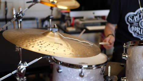 A-musician-playing-his-drum-set-in-a-garage-hitting-a-large-ride-cymbal-in-slow-motion