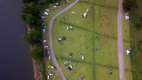Evacuation-camp-near-the-Warragamba-bushfire-with-vehicles-and-tents-seen-from-above,-Aerial-drone-bird's-eye-view-lowering-shot