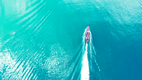 Langes-Boot,-Das-über-Leuchtend-Türkisfarbenes-Meerwasser-Segelt,-Das-Als-Spiegel-Wunderschönes-Sonnenlicht-Nahe-Der-Küste-Einer-Tropischen-Insel-In-Barbados-Reflektiert