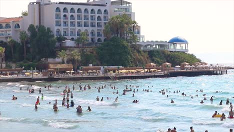 Playa-De-Damas-En-Kusadasi-En-Turquía,-Con-Hoteles-En-La-Costa-Y-Mucha-Gente-En-El-Mar.
