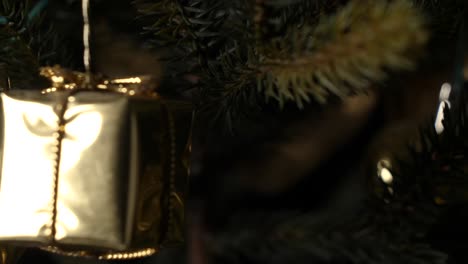 Reveal-of-golden-glittery-gift-box-on-a-christmas-tree,-sliding-shot