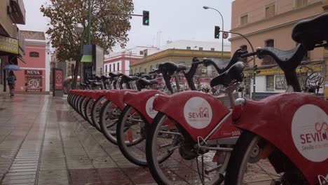 Bicycles-at-Sevici-bikes-rental-station-on-rainy-day-in-Seville,-Spain