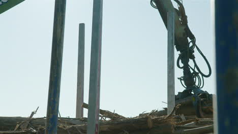 Crane-arm-lifts-eucalyptus-tree-logs-onto-stack,-60fps,-lens-flare