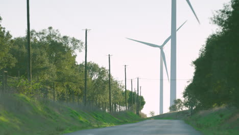 Large-wind-turbines-rise-in-distance-near-rural-countryside-road