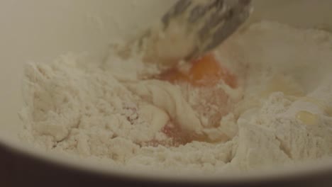 Macro-shot-mixing-egg-yolks-into-flour-with-fork