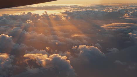 Aerial-view-from-airplane-window-of-white-clouds-in-golden-sky
