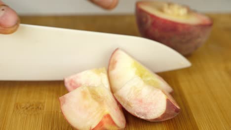 Close-up-slow-motion-of-peaches-being-sliced-with-a-ceramic-knife