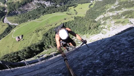 A-young-man-exploring-the-Swiss-Alps-while-climbing-up-the-mountain-by-carabiner-and-rope-to-Furenalp-via-Ferrata